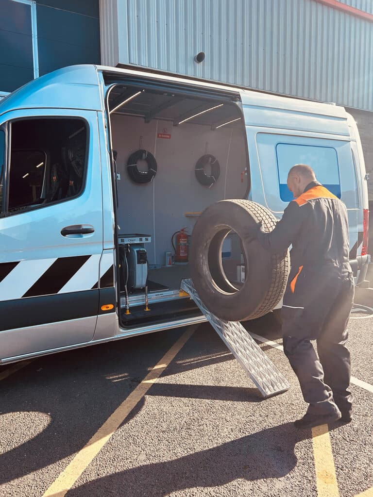Picture of a man rolling a tyre into a white On Board Power work van