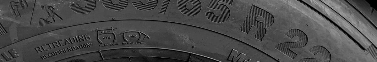 Close-up view of a truck tire sidewall showing detailed tyre markings, including size, load capacity, and speed rating, with a focus on understanding tyre labeling