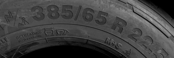 Close-up view of a truck tire sidewall showing detailed tyre markings, including size, load capacity, and speed rating, with a focus on understanding tyre labeling